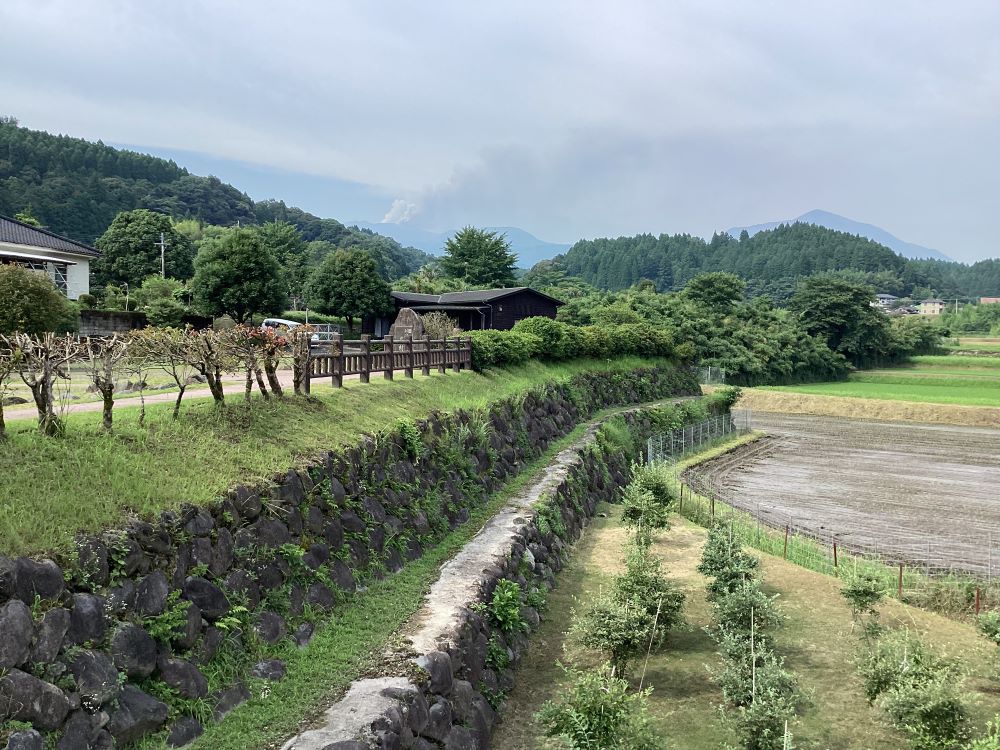 明るい農村の蔵から見える、新燃岳の噴火の様子（2025年7月）